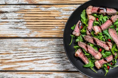 Biberli Fransız bifteği ve roka salatası. Beyaz ahşap arka plan. Üst Manzara. Boşluğu kopyala.