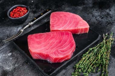 Mermer kesim tahtasında çiğ ton balığı bifteği. Siyah arka plan. Üst görünüm.