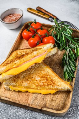 Kesme tahtasında ev yapımı kızarmış jambonlu ve peynirli sandviç. Beyaz arka plan. Üst görünüm.