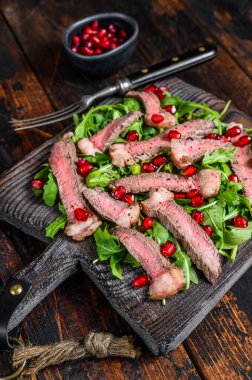 Izgara biftek salatası, roka, nar ve sebze. Koyu ahşap arka plan. Üst görünüm.