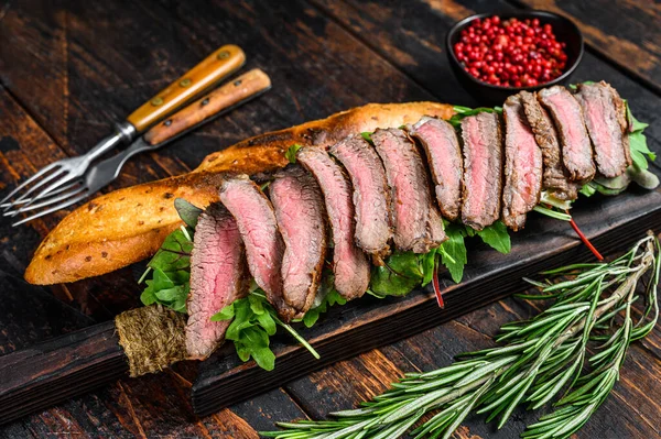 Flank Steak Baguette三明治 切菜板上有牛油果 深色木制背景 顶部视图 — 图库照片