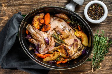 Fırında keçi budu pişirdim. Ahşap arka plan. Üst görünüm.