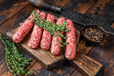 Kesme tahtasının üzerinde çiğ et, lula kebabı sosisi. Koyu ahşap arka plan. Üst görünüm.