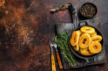 Kesme tahtasının üzerinde kızarmış mürekkep balığı halkaları. Karanlık arka plan. Üst Manzara. Boşluğu kopyala.