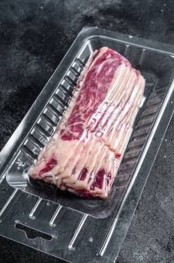 Vakum ambalajında çiğ domuz pastırması. Siyah arka plan. Üst görünüm.