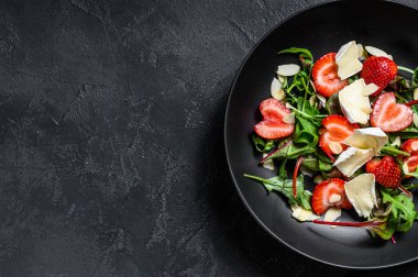 Çilekli peynirli salata, fındık, pazı ve roka. Siyah arka plan. Üst Manzara. Boşluğu kopyala.