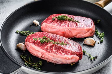 Tavada çiğ bıçaklı biftek. Gri arka plan. Üst görünüm.