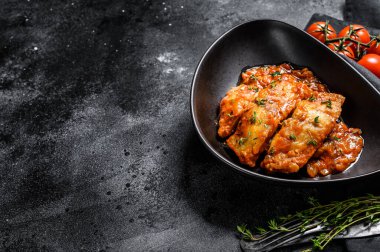 Domates soslu fırında halibut balığı. Siyah arka plan. Üst Manzara. Boşluğu kopyala.