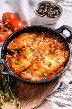 Tavada pişmiş halibut balığı ve domates sosu. Beyaz ahşap arka plan. Üst görünüm.