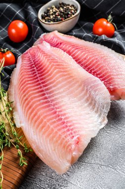 Kesme tahtasındaki çiğ balık tilapiası. Gri arka plan. Üst görünüm.