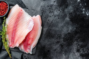 Taze tilapia filetosu ve kekik. Siyah arka plan. Üst Manzara. Boşluğu kopyala.