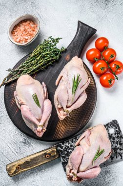 Çiğ bıldırcın hazırlama tahtasında et satırıyla. Beyaz arka plan. Üst görünüm.