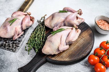 Çiğ bıldırcın hazırlama tahtasında et satırıyla. Beyaz arka plan. Üst görünüm.