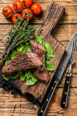 Kesme tahtasının üzerinde ızgara kesilmiş etekli et bifteği. Ahşap arka plan. Üst görünüm.