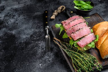 Baget ton balıklı biftekli sandviç ve yanında roka. Siyah arka plan. Üst Manzara. Boşluğu kopyala.