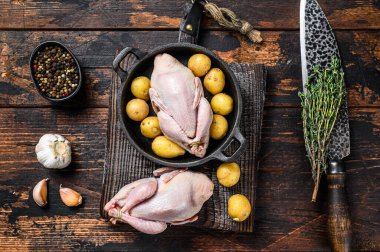 Pişmemiş çiğ bıldırcınlar tavada pişirilmeye hazır. Koyu ahşap arka plan. Üst görünüm.