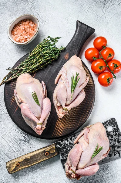 Çiğ bıldırcın hazırlama tahtasında et satırıyla. Beyaz arka plan. Üst görünüm.