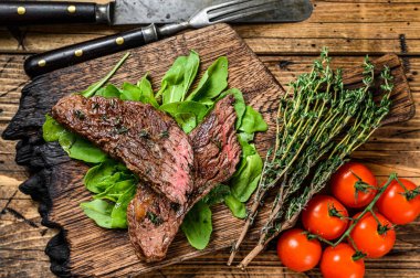 Kesme tahtasının üzerinde ızgara kesilmiş etekli et bifteği. Ahşap arka plan. Üst görünüm.