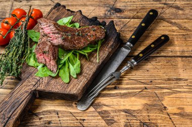 Kesme tahtasının üzerinde ızgara kesilmiş etekli et bifteği. Ahşap arka plan. Üst Manzara. Boşluğu kopyala.