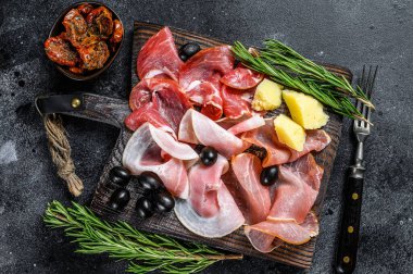 Tütsülenmiş et, kurutulmuş jambon, kurutulmuş et, tuzlanmış et, reçel ve bitkiler. Siyah arka plan. Üst görünüm.