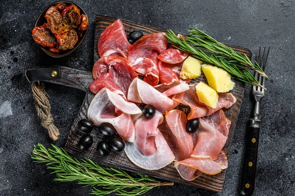 Tütsülenmiş et, kurutulmuş jambon, kurutulmuş et, tuzlanmış et, reçel ve bitkiler. Siyah arka plan. Üst görünüm.