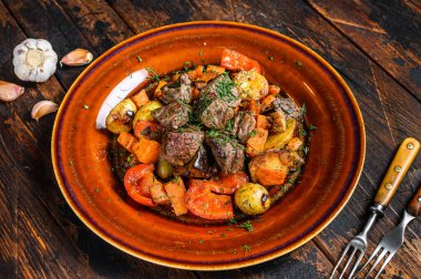 Sığır eti, patates, havuç ve ottan yapılmış İrlanda güveci. Koyu ahşap arka plan. Üst görünüm.