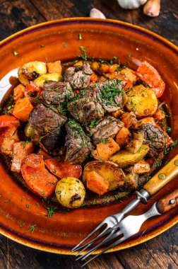 Sığır eti, patates, havuç ve ottan yapılmış İrlanda güveci. Koyu ahşap arka plan. Üst görünüm.