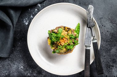 Dilimlenmiş biftek ve patatesli salata yaprakları. Siyah arka plan. Üst görünüm