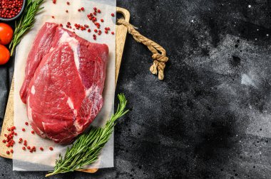 Kesme tahtasındaki çiğ sığır eti. Siyah arka plan. Üst Manzara. Boşluğu kopyala.