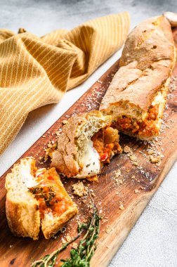 Patlıcan, domates ve peynirle doldurulmuş baget. Lezzetli bir İtalyan yemeği, lezzetli atıştırmalıklar, ev yapımı sandviç. Gri arka plan. Üst görünüm.