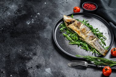 BBQ deniz levreği, roka ve kızarmış levrek. Siyah arka plan. Üst Manzara. Boşluğu kopyala.