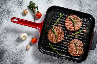 Biftek köfteleri sıcak ızgara tavada cızırdıyor. Beyaz arka plan. Üst görünüm.