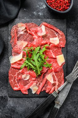 Siyah tabakta parmesan peyniri ve roka ile sığır eti carpaccio. Siyah arka plan. Üst görünüm.