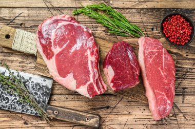 Çiğ siyah angus bifteği fileto Mignon, pirzola ya da kovboy, Striploin ya da New York. Ahşap arka plan. Üst görünüm.
