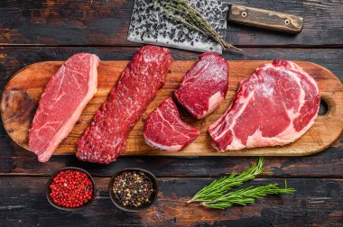 Çiğ sığır fileto fileto fileto, pirzola, striploin veya New York, etek, pala çeşitleri. Ahşap arka plan. Üst görünüm.