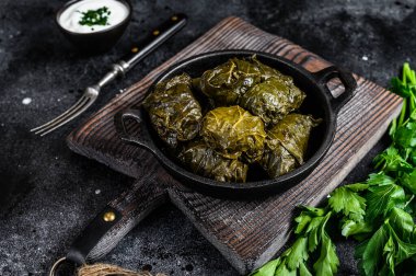 Dolma stuffed grape leaves with rice and meat. Black background. Top view. clipart