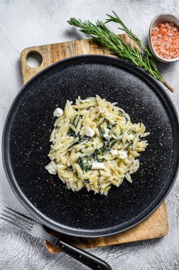 Ispanak ve Feta orzo makarna tabakta. Beyaz arka plan. Üst görünüm.