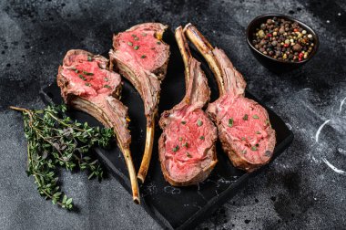 Mermer bir tahtanın üzerinde kuzu kaburga pirzolası biftek. Siyah arka plan. Üst görünüm.