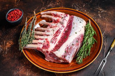 Çiğ taze kuzu pirzolası ve yeşil otlar. Karanlık arka plan. Üst görünüm.