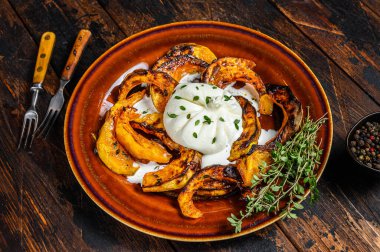 Peynirli Burrata salatası ve bir tabakta fırında balkabağı. Koyu ahşap arka plan. Üst görünüm.