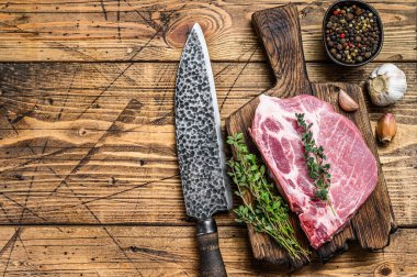 Kesme tahtasında bıçakla taze çiğ mermer et biftekleri. Ahşap arka plan. Üst Manzara. Boşluğu kopyala.