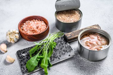 Konserve ton balığı konservesi, bütün ve doğranmış. Gri ahşap arka plan. Üst görünüm.