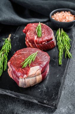 Taş bir tahtanın üzerinde çiğ biftek fileto. Siyah arka plan. Üst görünüm.