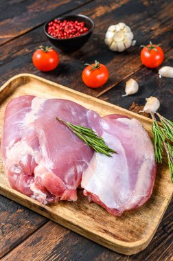 Tahta tepside çiğ kemiksiz hindi filetosu. Karanlık arka plan. Üst görünüm.