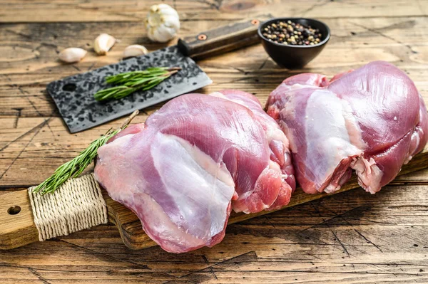 Raw boneless Turkey thigh fillet on a chopping Board. wooden background. Top view.