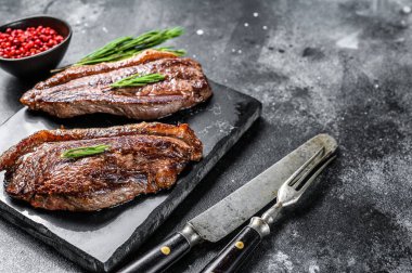 Kaya kesme tahtasında ızgara biftek. Siyah arka plan. Üst Manzara. Boşluğu kopyala.