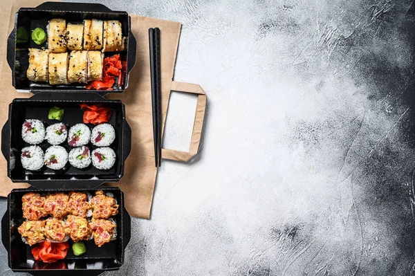 The sushi rolls in the delivery package, ordered in sushi take-out restaurant. Gray background. Top view. Copy space.