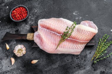Baharatlı taze çiğ beyaz balık fileto Pangasius. Siyah arka plan. Üst görünüm.