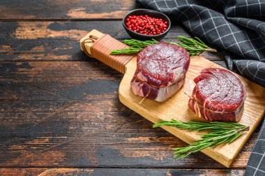 Kesme tahtasının üzerinde çiğ biftek fileto fileto. Karanlık ahşap arka plan. Üst Manzara. Boşluğu kopyala.