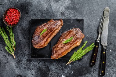 Kaya kesme tahtasında ızgara biftek. Siyah arka plan. Üst görünüm.